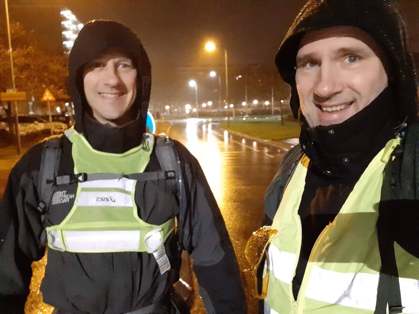 Evert en zijn broer René tijdens een nachtelijke trainingswandeling in de regen, met hoofdlampje en reflecterend vest