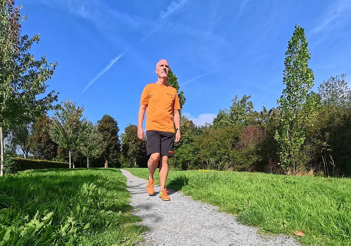 Wandeltrainer Evert Aldewereld wandelt op barefootschoenen over een grindpad in het groen
